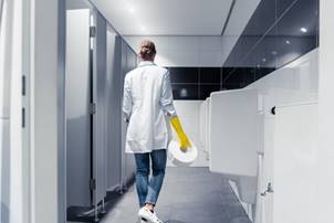 Waschraumservice: Eine Reinigungskraft arbeitet in einem großen, modernen Waschraum.